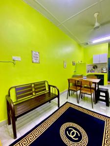 a green room with a bench and a table and a tableablish at AISY HOMESTAY - Rumah 4,5 in Kampong Tanjong Karang