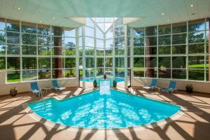 uma piscina interior num quarto amplo com janelas em Four Points by Sheraton Richmond em Midlothian