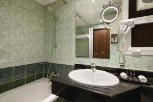 a bathroom with a sink and a tub and a mirror at Howard Johnson by Wyndham Abu Dhabi Downtown in Abu Dhabi +21 photos