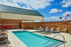 une piscine avec des chaises et un bâtiment dans l'établissement Four Points by Sheraton Dallas Fort Worth Airport North, à Coppell