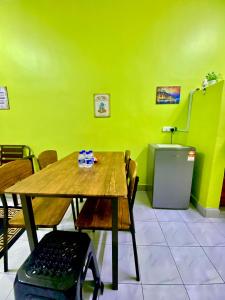 a dining room with a table and a green wall at AISY HOMESTAY - Rumah 4,5 in Kampong Tanjong Karang