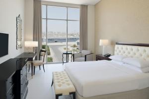 Delta Hotels by Marriott Dubai Investment Park في دبي: غرفة نوم بسرير ابيض ونافذة كبيرة
