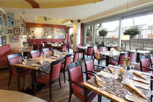 a restaurant with wooden tables and chairs and a large window at Courtyard by Marriott Duesseldorf Hafen in Düsseldorf