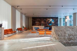 a lobby with orange chairs and a stone wall at The Jaffa, a Luxury Collection Hotel, Tel Aviv in Tel Aviv