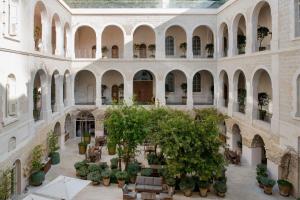 an indoor courtyard with trees and tables and chairs at The Jaffa, a Luxury Collection Hotel, Tel Aviv in Tel Aviv