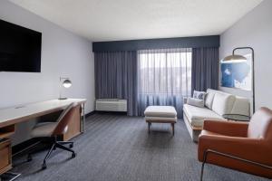 a hotel room with a couch and a desk and a tv at Courtyard by Marriott Boulder Broomfield in Louisville