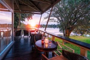 een veranda met tafels en stoelen en uitzicht op een meer bij Protea Hotel by Marriott Zambezi River Lodge in Katima Mulilo