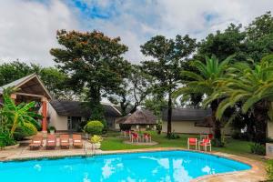 - une piscine en face d'une maison avec des chaises et des tables dans l'établissement Protea Hotel by Marriott Zambezi River Lodge, à Katima Mulilo