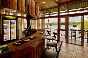 a bar in a restaurant with a view of the water at Protea Hotel by Marriott Zambezi River Lodge in Katima Mulilo