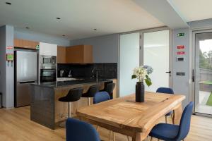 a kitchen with a wooden table and blue chairs at King´s View (Heated Pool and Sea View) in Estreito da Calheta
