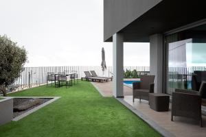 a patio with green grass and a table and chairs at King´s View (Heated Pool and Sea View) in Estreito da Calheta