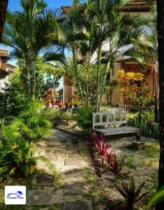 un jardin avec un banc et des palmiers dans l'établissement Casa Tua Pipa, à Pipa
