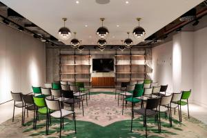 uma sala de conferências com cadeiras verdes e um ecrã em Bankside Hotel, Autograph Collection em Londres