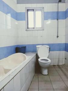 a bathroom with a toilet and a tub and a window at Cybhouse in Yaoundé