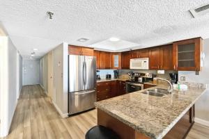 a kitchen with wooden cabinets and a stainless steel refrigerator at 108 Beach Place Condos in St Pete Beach