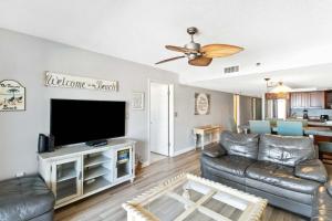 108 Beach Place Condos في سانت بيتي بيتش: غرفة معيشة مع أريكة وتلفزيون بشاشة مسطحة