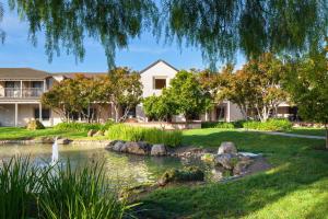 a house with a pond in front of a yard at Four Points by Sheraton - Pleasanton in Pleasanton