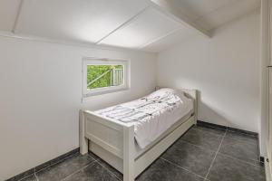 a small white bedroom with a bed and a window at De Zeevijver Oostduinkerke in Oostduinkerke