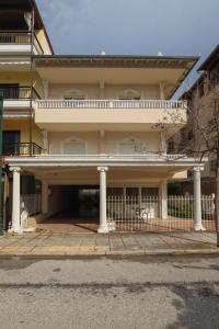 een oud huis met zuilen en een balkon bij Indigo luxury apartments in Olympiakí Aktí