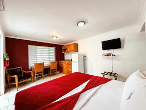 a bedroom with a red and white bed and a kitchen at Ladybugs Apartments in Palm-Eagle Beach