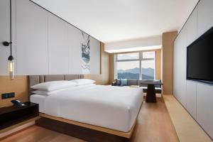 a bedroom with a white bed and a flat screen tv at Fairfield by Marriott Shenshan Special Cooperation Zone in Haifeng