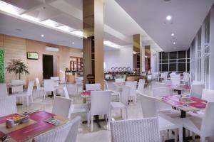 a restaurant with white tables and white chairs at favehotel Simpang Lima - Semarang in Semarang