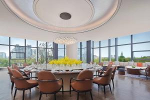 Yancheng Marriott Hotel في يانتشنغ: غرفة طعام كبيرة مع طاولة وكراسي