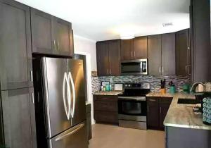 a kitchen with wooden cabinets and a stainless steel refrigerator at Cozy Marine Corps Home Near MCRD w/ a Beach Pass in Beaufort