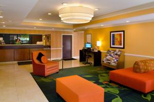 a hotel lobby with orange chairs and a desk at SureStay Plus by Best Western Fenton in Fenton