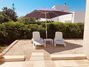 two chairs and an umbrella on a patio at La Racioppola in Ostuni