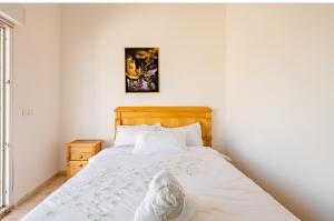 - une chambre avec un lit blanc et une tête de lit en bois dans l'établissement Elaaz Horse Farm, à Azemmour