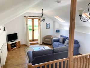 sala de estar con sofá y TV en Cloister Park Cottages, en Frithelstock