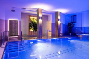 a large swimming pool in a hotel with blue lighting at Wellness Hotel pod Kyčmolem in Horní Lomná