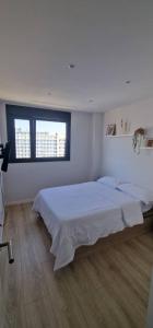 a white room with two beds and a window at Habitación confortable para parejas (1) in Barcelona