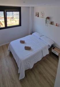 um quarto com uma cama branca com duas toalhas em Habitación confortable para parejas (1) em Barcelona