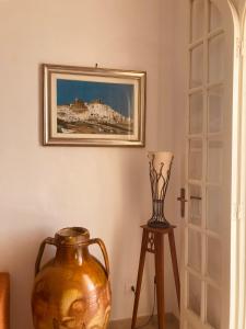 a vase sitting on a stool next to a painting on the wall at La Racioppola in Ostuni