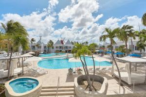 einen Pool im Resort mit Palmen und Stühlen in der Unterkunft Courtyard by Marriott Aruba Resort in Palm-Eagle Beach