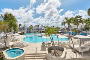 een zwembad in het resort met palmbomen en stoelen bij Courtyard by Marriott Aruba Resort in Palm-Eagle Beach