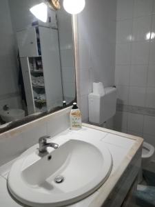 uma casa de banho com um lavatório branco e um espelho. em La casa di Eleonora em Nápoles