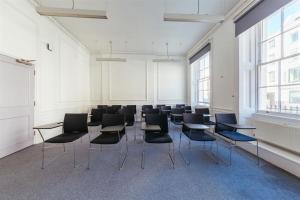 a room with desks and chairs in a classroom at John Adams Hall in London