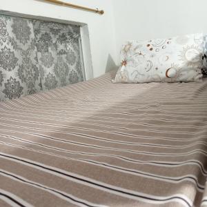 a bed with a gray blanket and pillows on it at Transient with bedroom near Padre Pio Church in San Felix +9 photos