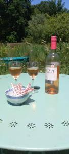 uma garrafa de vinho e dois copos de vinho numa mesa em Las Cafourques Chambre d'Hotes em Ségalas