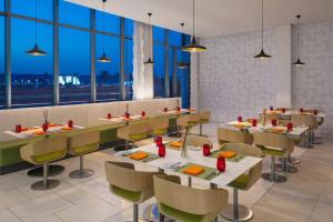 a dining room with tables and chairs and windows at Aloft Dhahran Hotel in Al Khobar