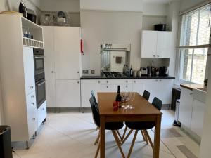 ロンドンにあるLovely newly refurbished apartment in Batterseaの白いキャビネットと木製テーブル付きのキッチン