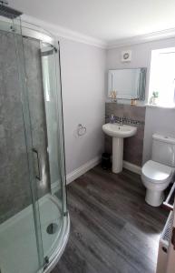 uma casa de banho com um chuveiro, um WC e um lavatório. em Oakcroft em Sidmouth