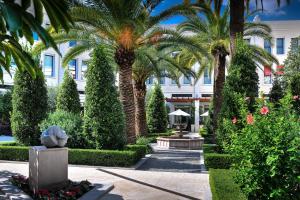 a garden with palm trees and a building at The Westin Valencia in Valencia