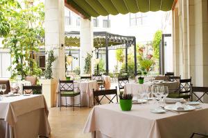 um restaurante com mesas e cadeiras com toalha de mesa branca em The Westin Valencia em Valência