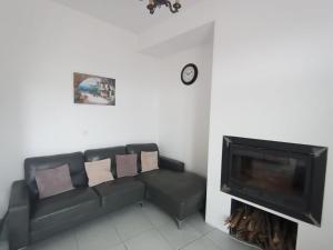 a living room with a black couch and a fireplace at Le passage de Gardie in Gardie