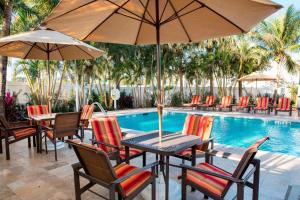 een tafel en stoelen met parasols naast een zwembad bij Four Points by Sheraton Fort Lauderdale Airport/Cruise Port in Fort Lauderdale