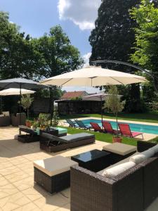 een patio met tafels en parasols naast een zwembad bij Maison de la Comtesse in Cosne-dʼAllier